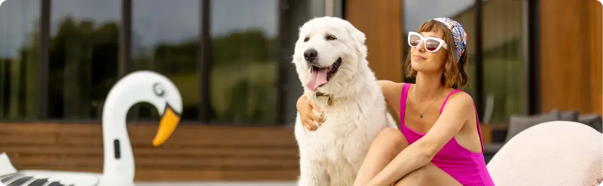 Woman with white dog by pool at pet-friendly hotel